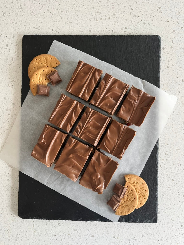 Delicious Tiffin pieces with chocolate, digestive biscuits, and cookies on a slate board.